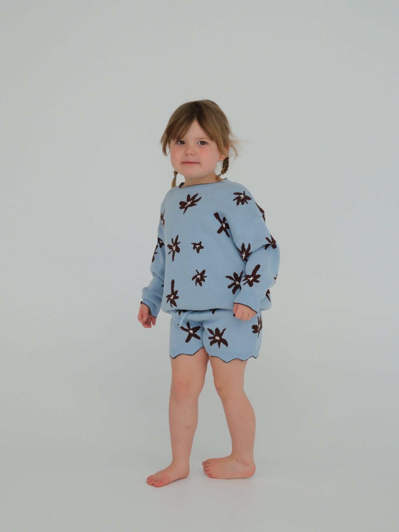Child wearing a blue pajama set with brown patterns on a plain background