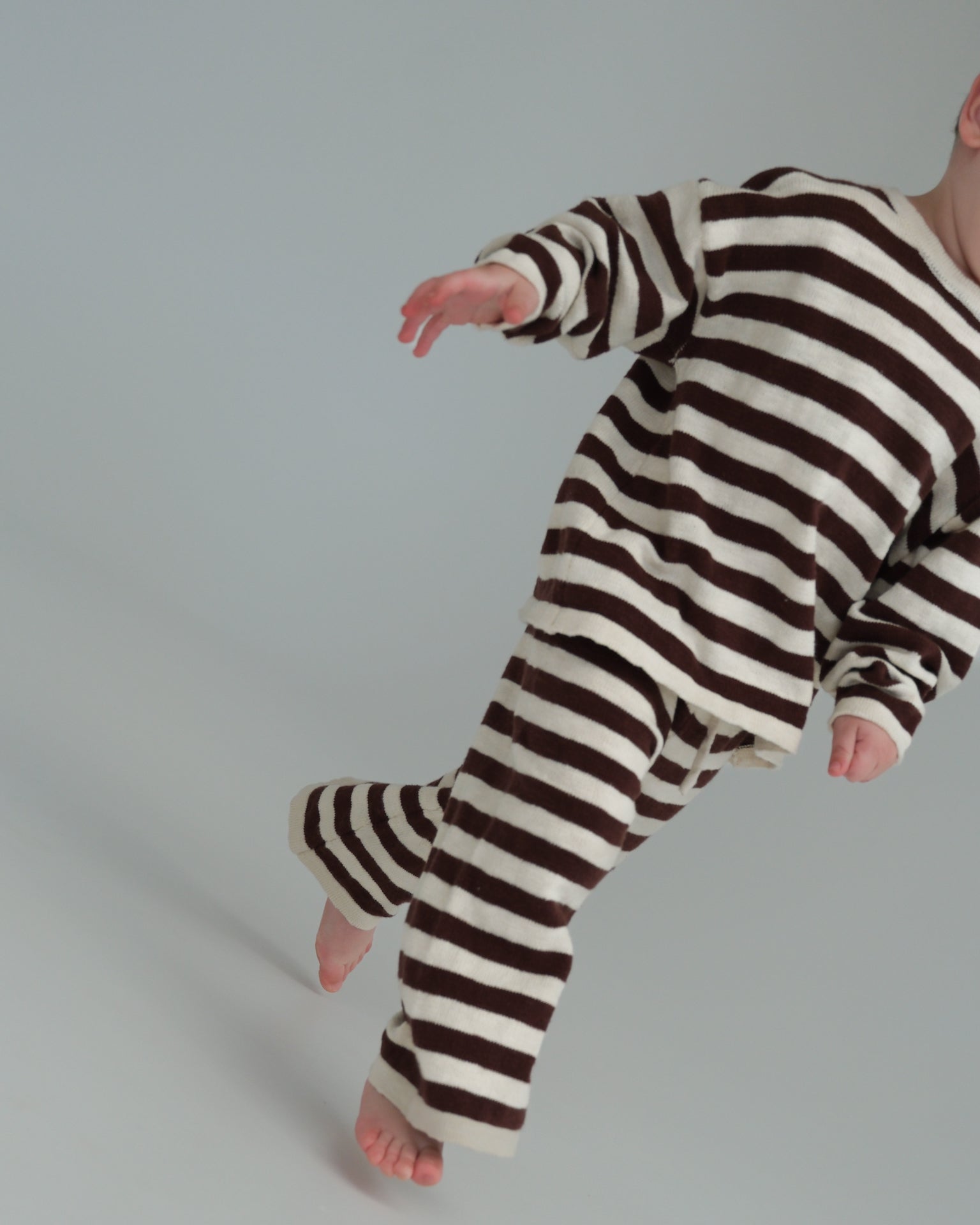 Person wearing a brown and white striped onesie on a plain background