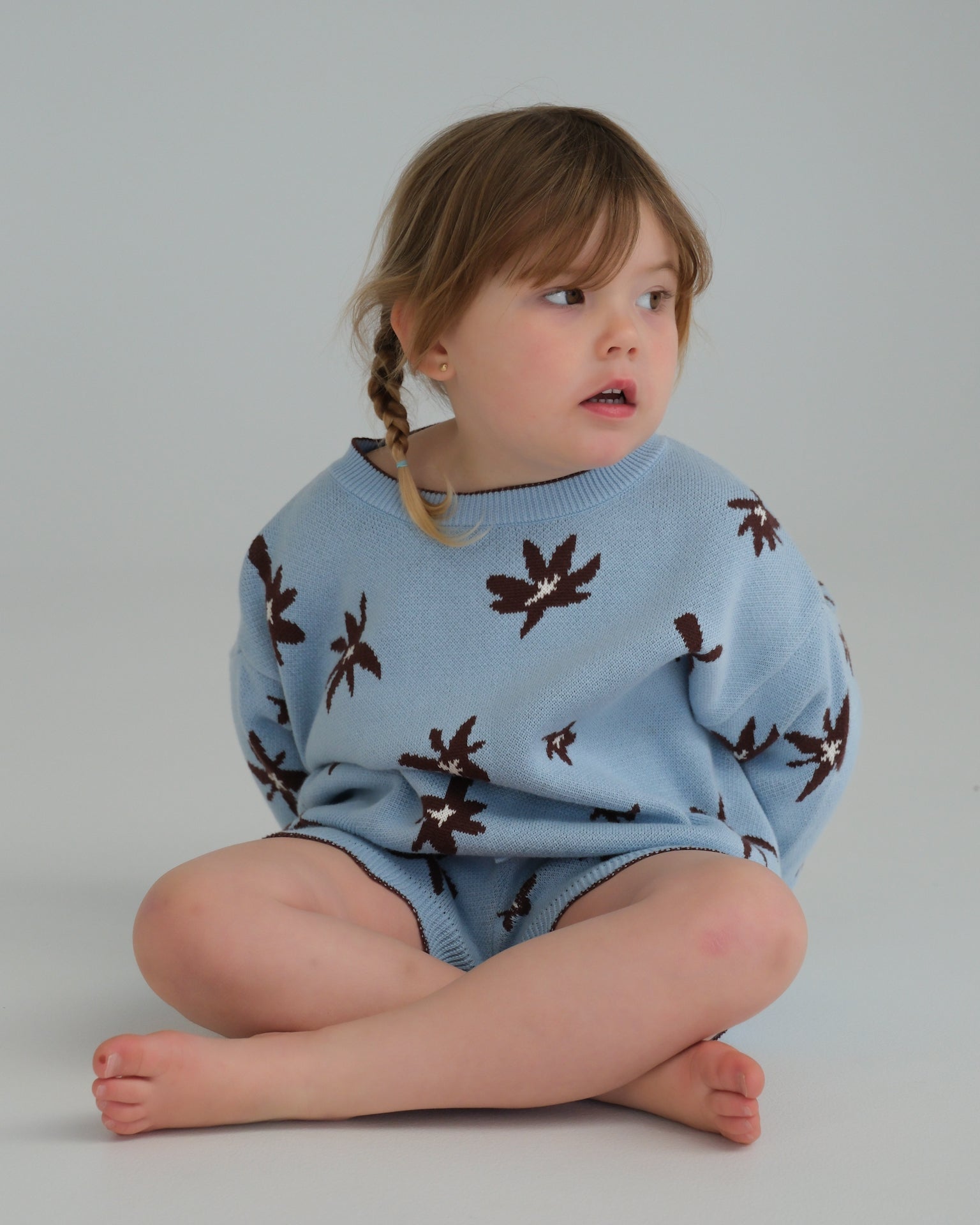 Child wearing a blue sweater with brown patterns on a plain background