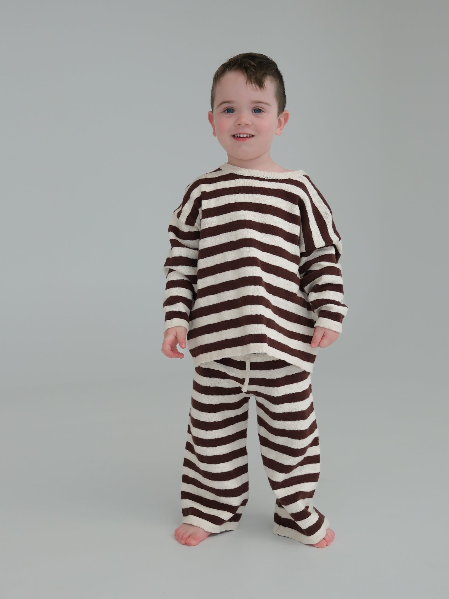 Child wearing a brown and white striped outfit on a plain background