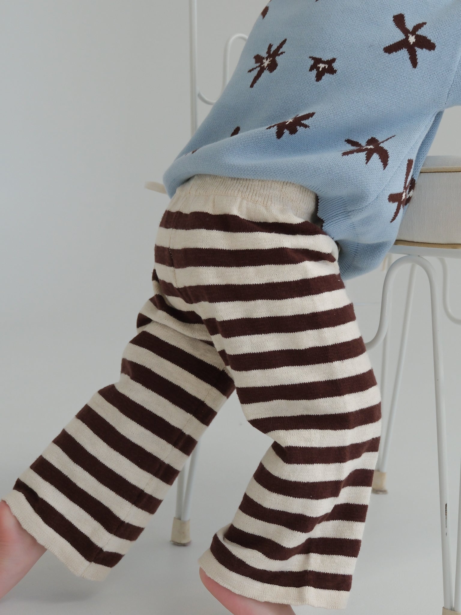 Brown and white striped pants worn by a child with a light blue shirt featuring brown patterns.